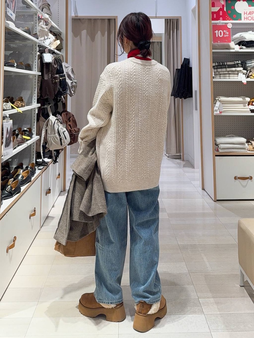 ブラウン系のボストンバッグ、ブルー系のデニムパンツ、ブラウン系のチェスターコートを着用したレディースの冬コーディネートの8枚目の写真