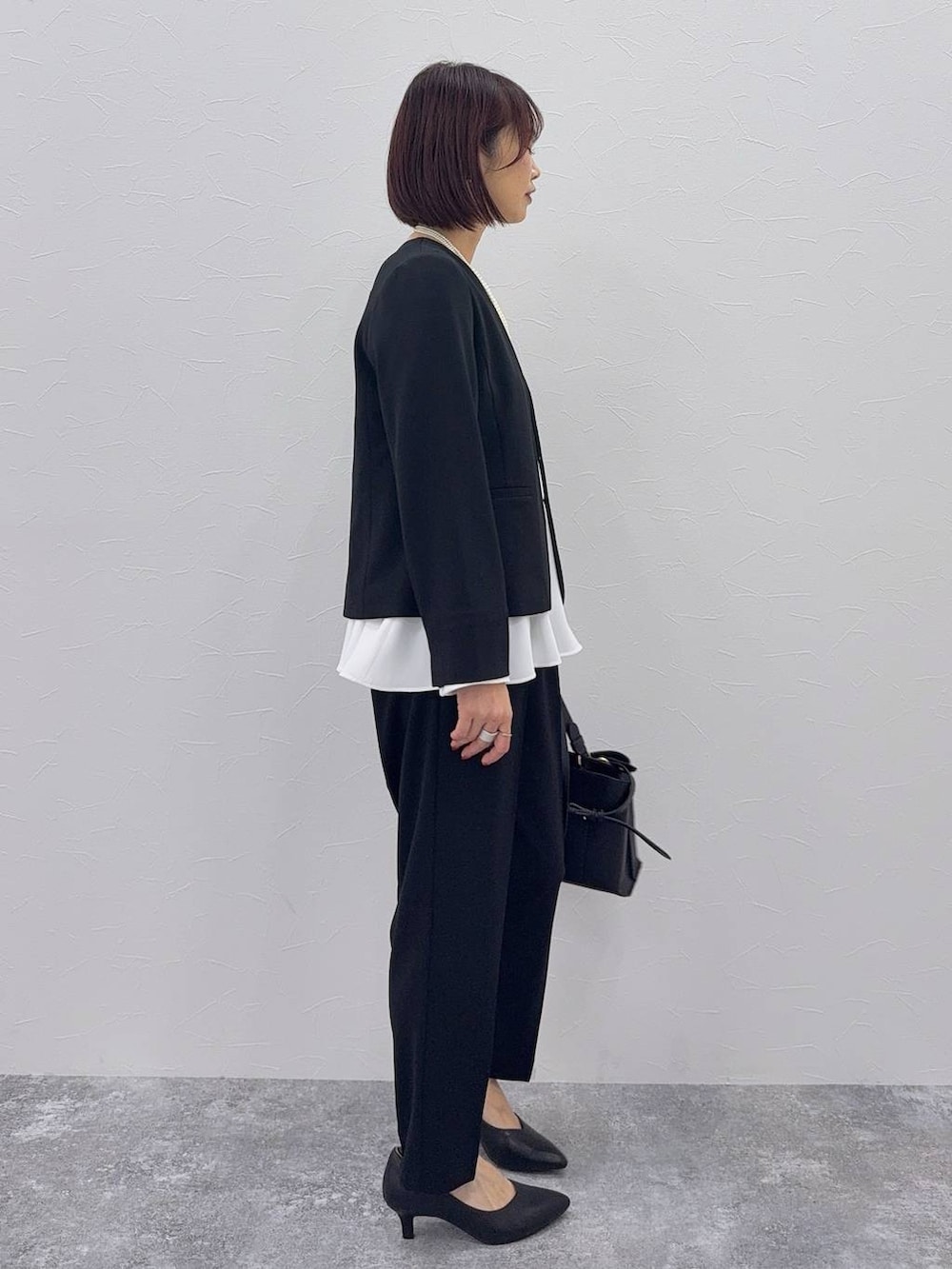 ブラック系のパンプス、ブラック系のセットアップ、その他のネックレスを着用したレディースの秋コーディネートの3枚目の写真