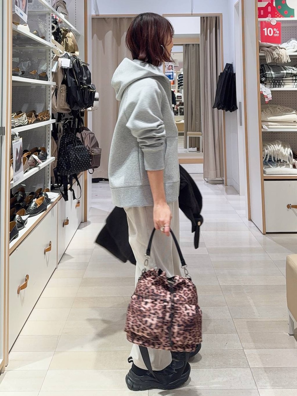 ブラック系のチェスターコート、グレー系のその他パンツ、ブラック系のスニーカーを着用したレディースの冬コーディネートの7枚目の写真