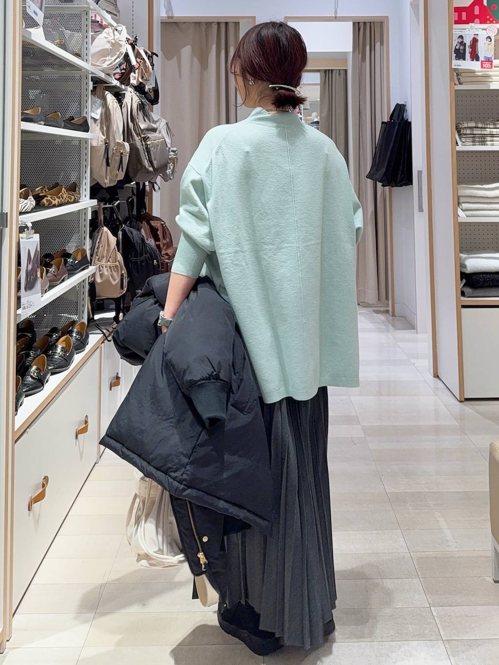 ホワイト系のショルダーバッグ、ブラック系のダウンジャケット/コート、ブラック系のブーツを着用したレディースの冬コーディネートの7枚目の写真