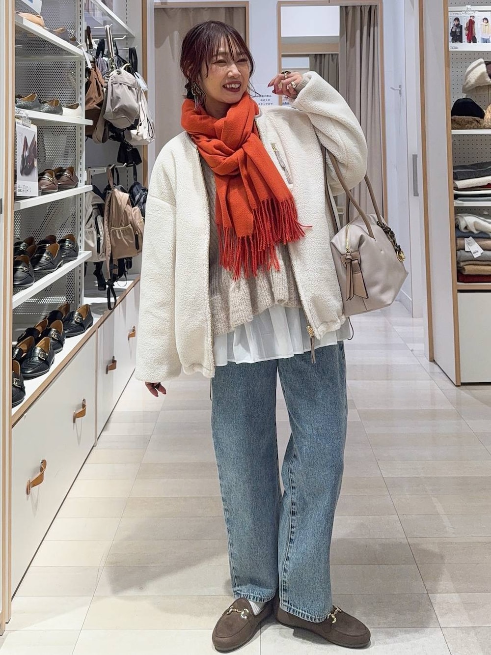 ホワイト系のボストンバッグ、ホワイト系のブルゾン、ブルー系のデニムパンツを着用したレディースの秋コーディネートの2枚目の写真