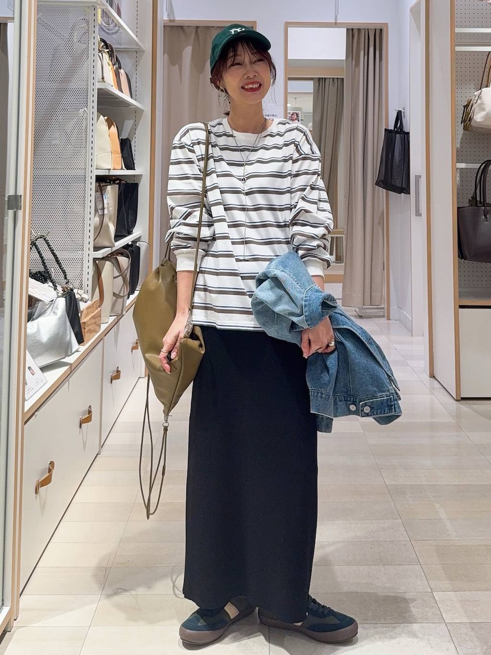 グリーン系のスニーカー、ブルー系のデニムジャケット、ブラック系のスカートを着用したレディースの冬コーディネートの2枚目の写真