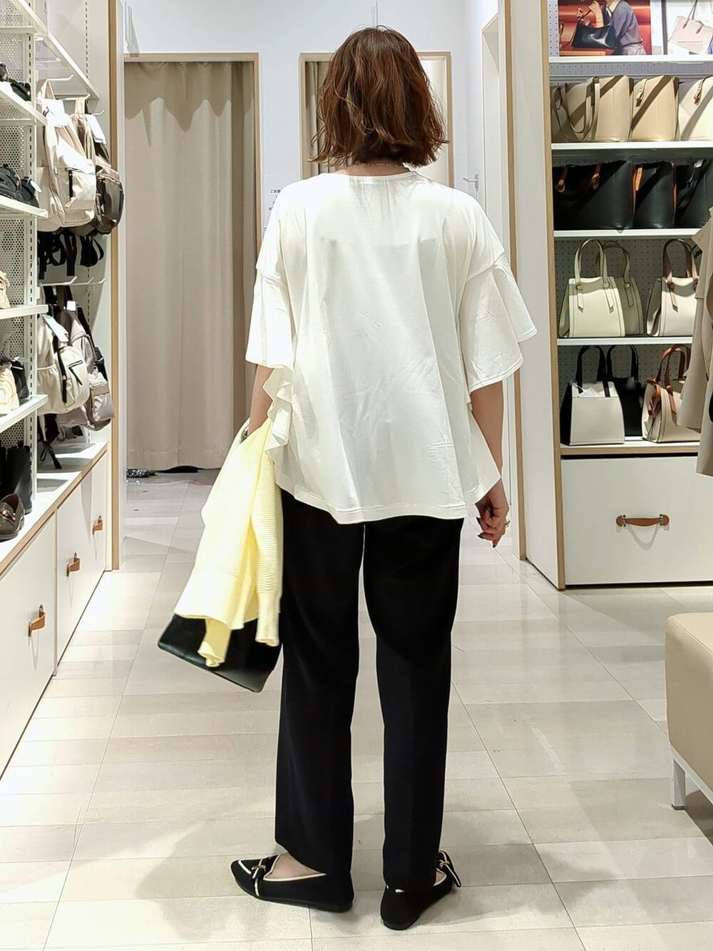 ブラック系のショルダーバッグ、イエロー系のカーディガン/ボレロ、その他のパンプスを着用したレディースの春コーディネートの7枚目の写真