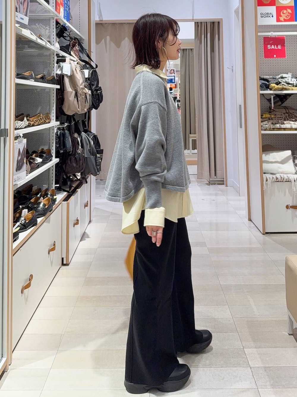 グレー系のニット/セーター、イエロー系のシャツ/ブラウス、ベージュ系のトートバッグを着用したレディースの冬コーディネートの3枚目の写真