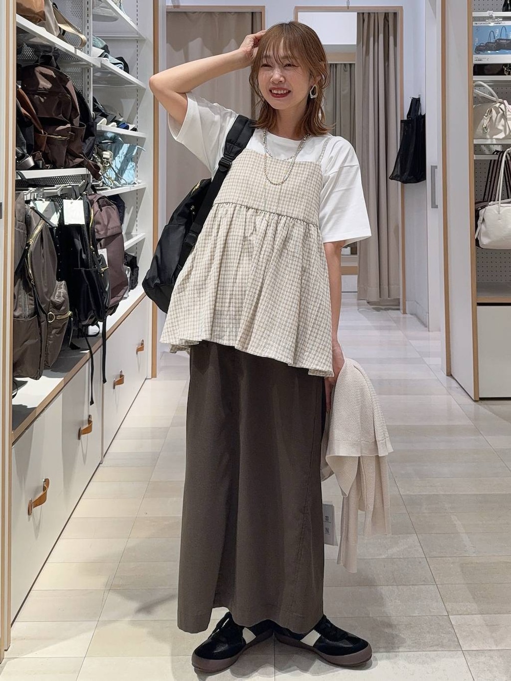 ブラック系のスニーカー、ブラック系のバックパック/リュック、ブラウン系のスカートを着用したレディースの春コーディネートの2枚目の写真