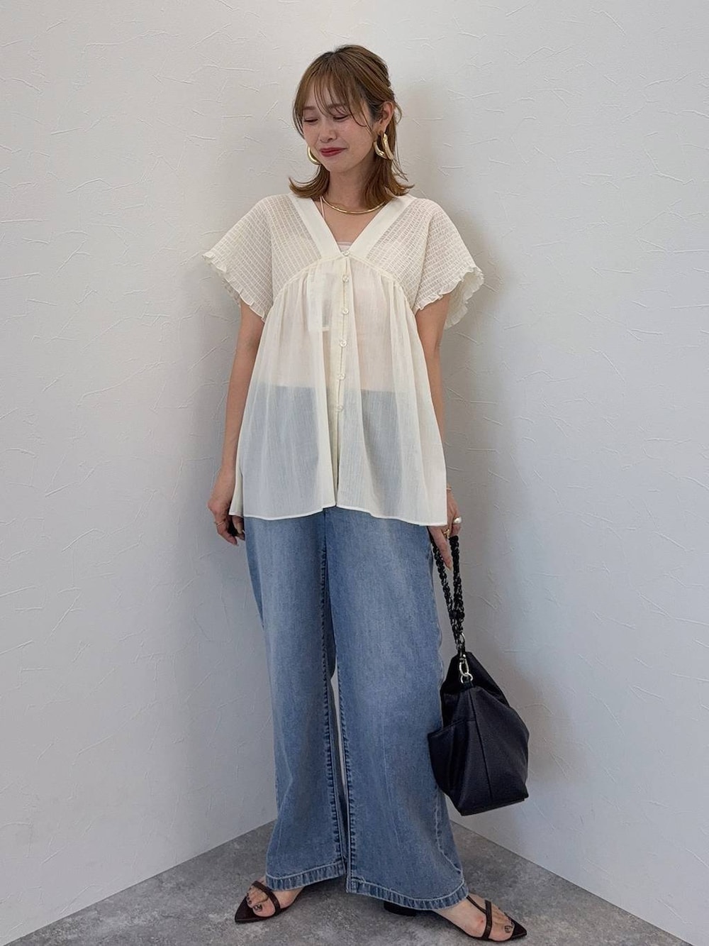ブルー系のデニムパンツ、ブラウン系のボストンバッグ、レッド系のシャツ/ブラウスを着用したレディースの夏コーディネートの2枚目の写真