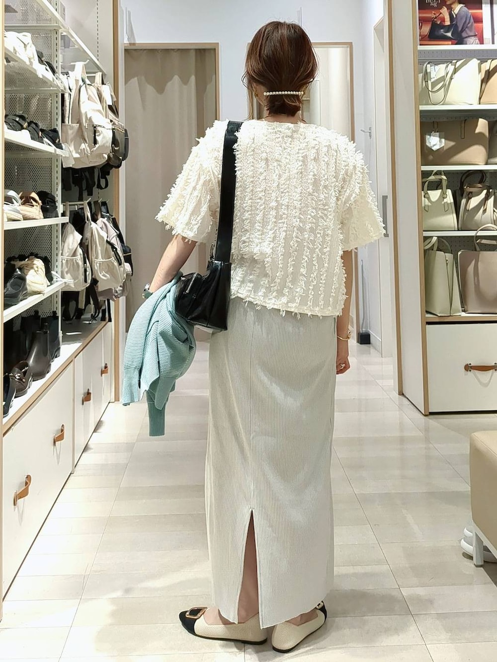 ブラック系のショルダーバッグ、グリーン系のカーディガン/ボレロ、グレー系のスカートを着用したレディースの春コーディネートの8枚目の写真