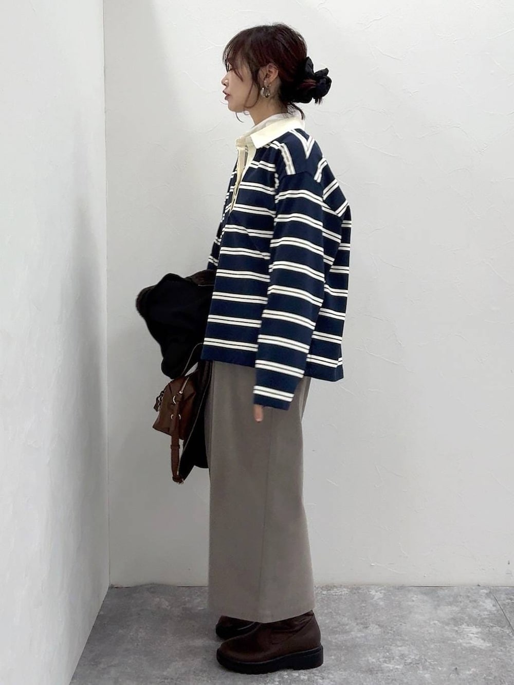 ブラック系のブルゾン、ブラウン系のスカート、ブラウン系のブーツを着用したレディースの冬コーディネートの7枚目の写真