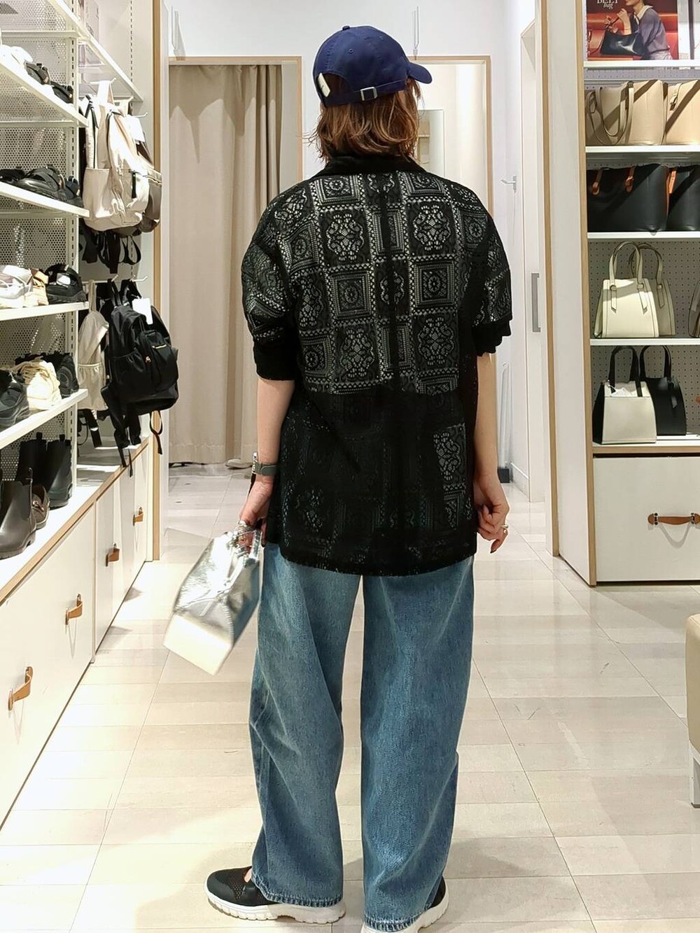 ブラック系のスニーカー、シルバー系のショルダーバッグ、ブルー系のデニムパンツを着用したレディースの春コーディネートの5枚目の写真