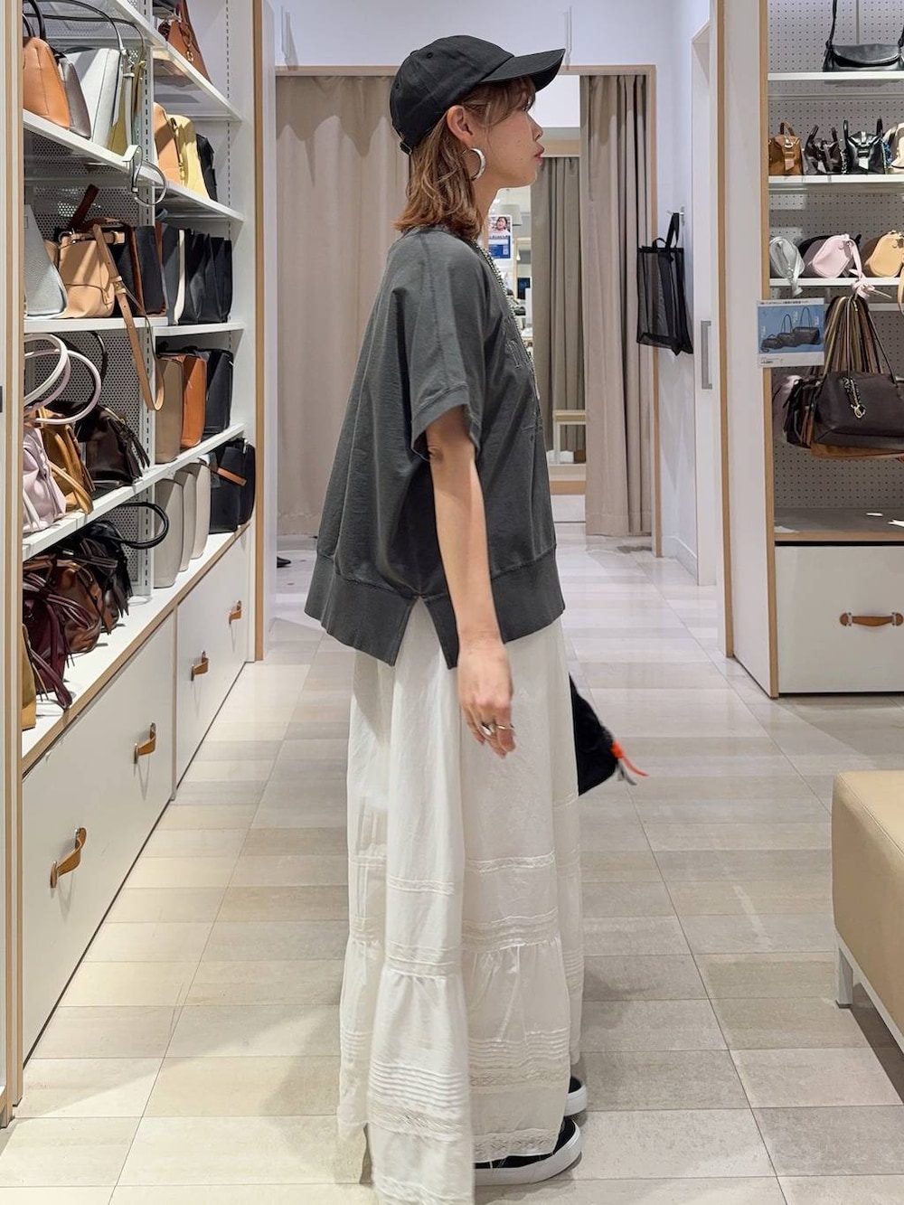 ブラック系のボストンバッグ、グレー系のパーカー、ホワイト系のスカートを着用したレディースの春コーディネートの7枚目の写真