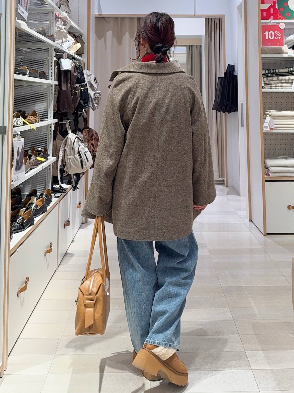 ブラウン系のボストンバッグ、ブルー系のデニムパンツ、ブラウン系のチェスターコートを着用したレディースの冬コーディネートの6枚目の写真