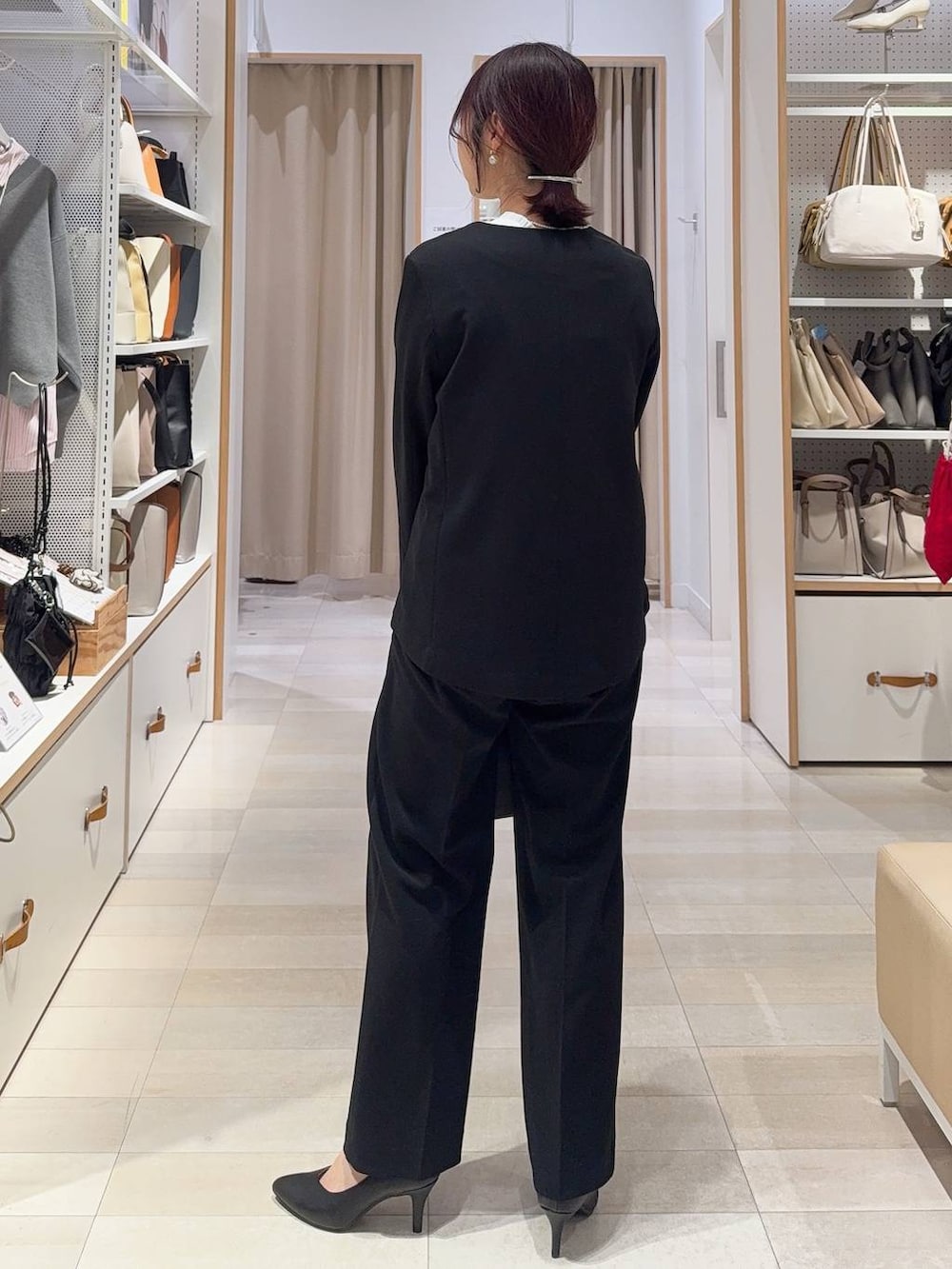 ブラック系のショルダーバッグ、ホワイト系のパンプス、ブラック系のセットアップを着用したレディースの冬コーディネートの4枚目の写真