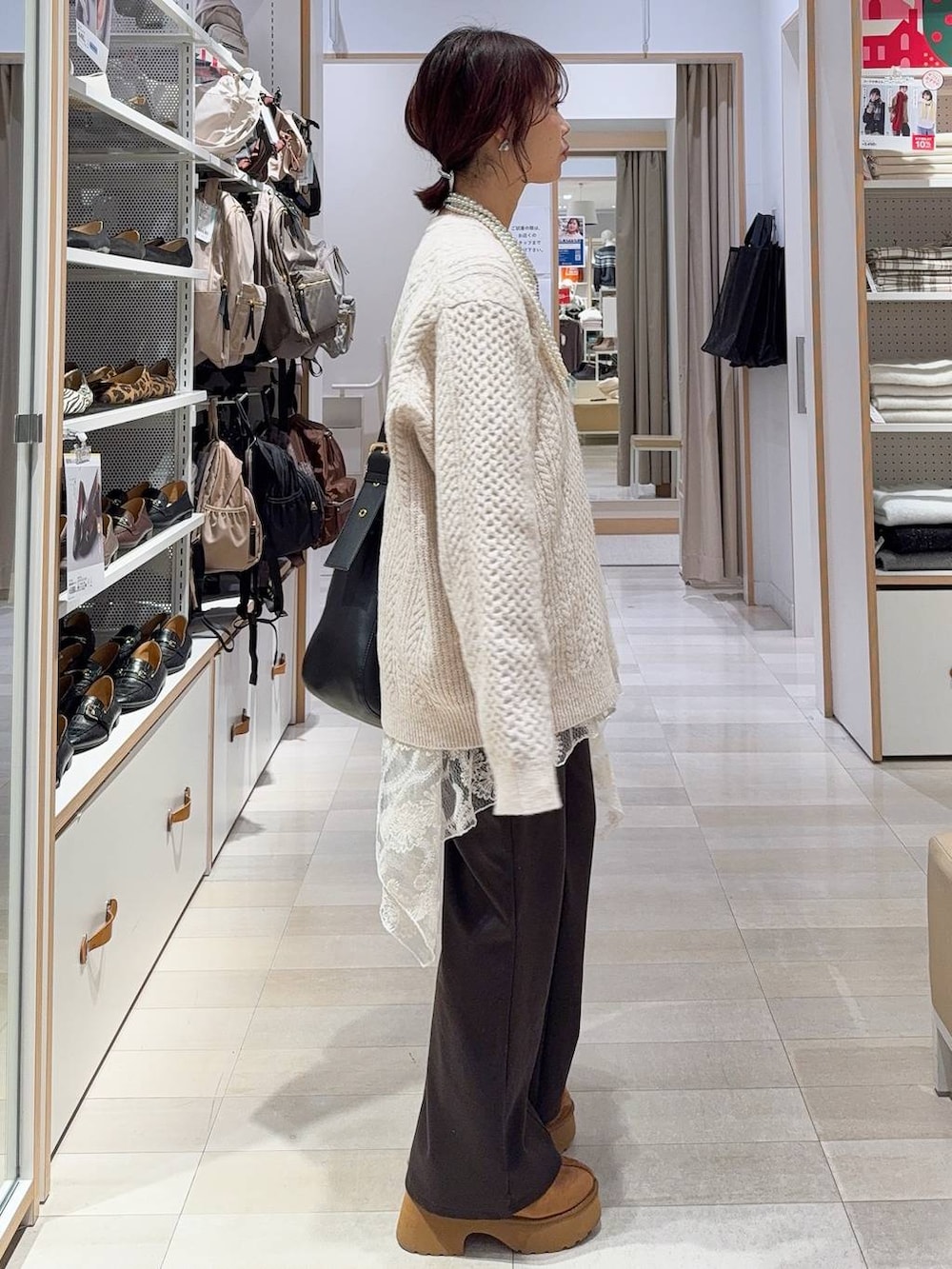 ブラック系のショルダーバッグ、イエロー系のブーツ、ホワイト系のニット/セーターを着用したレディースの冬コーディネートの8枚目の写真