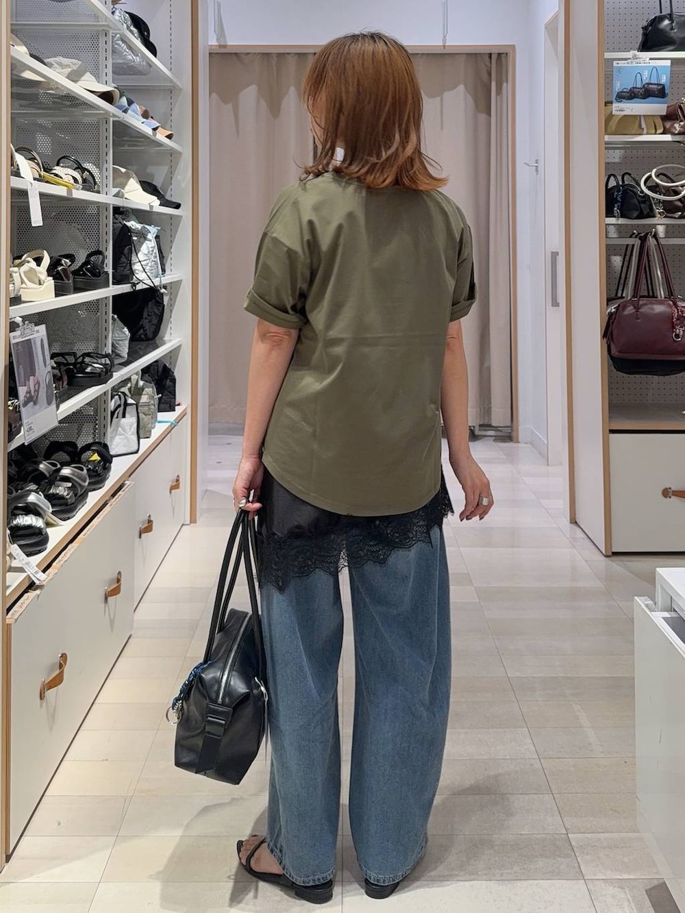ブラック系のボストンバッグ、ブルー系のデニムパンツ、グリーン系のTシャツ/カットソーを着用したレディースの夏コーディネートの4枚目の写真