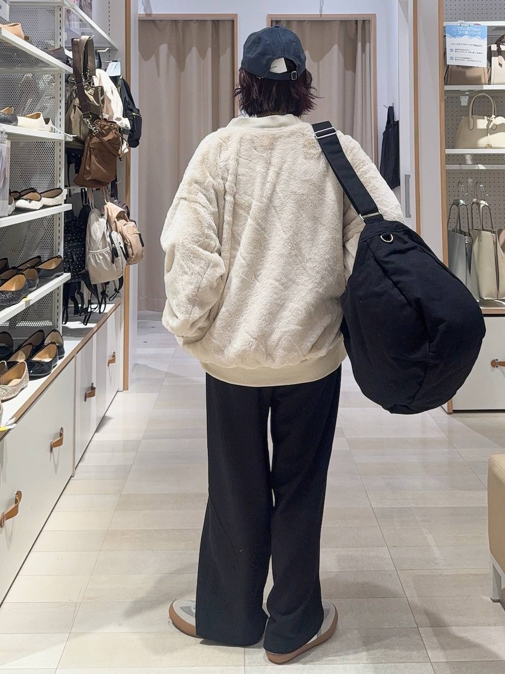 グレー系のスニーカー、ブラック系のショルダーバッグ、ベージュ系のブルゾンを着用したレディースの秋コーディネートの4枚目の写真