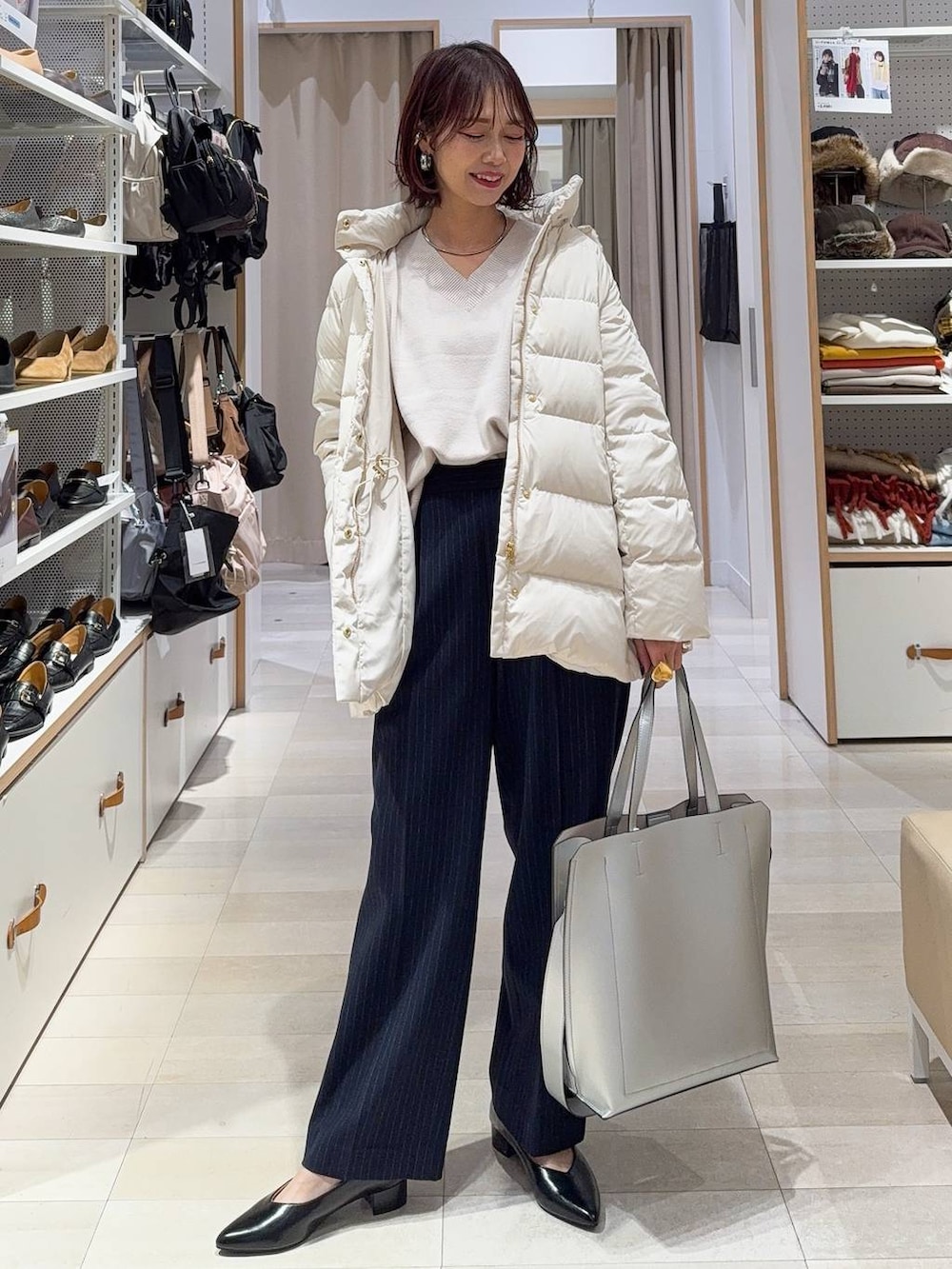 シルバー系のトートバッグ、ベージュ系のダウンジャケット/コート、ホワイト系のニット/セーターを着用したレディースの冬コーディネートの2枚目の写真