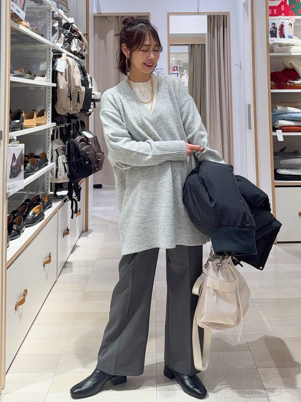 ホワイト系のショルダーバッグ、ブラック系のダウンジャケット/コート、ホワイト系のニット/セーターを着用したレディースの冬コーディネートの2枚目の写真