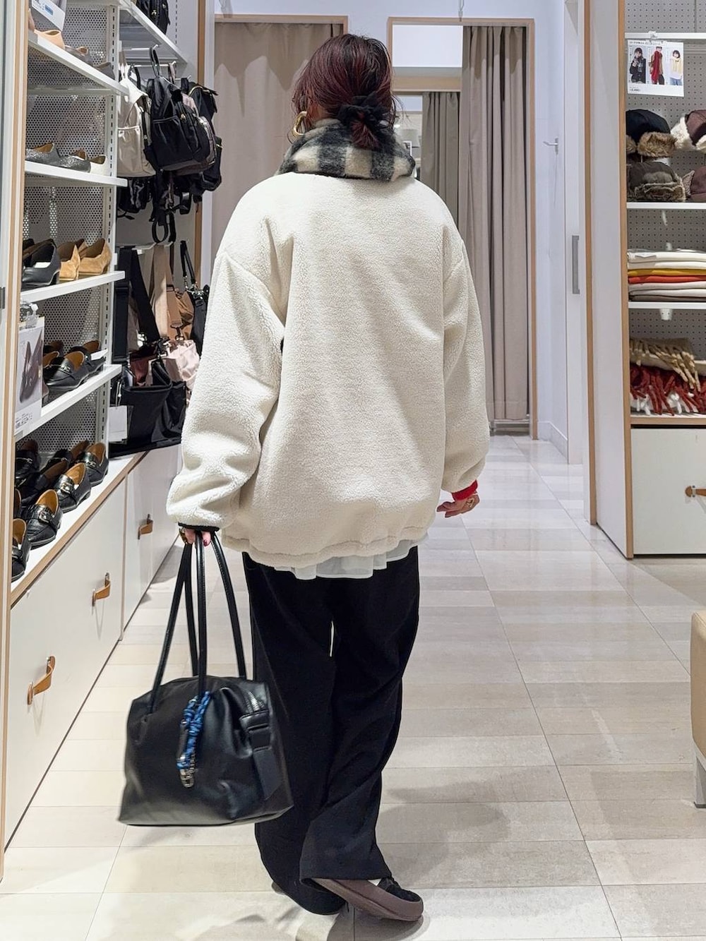 ブラック系のスニーカー、ブラウン系のボストンバッグ、ホワイト系のブルゾンを着用したレディースの冬コーディネートの5枚目の写真