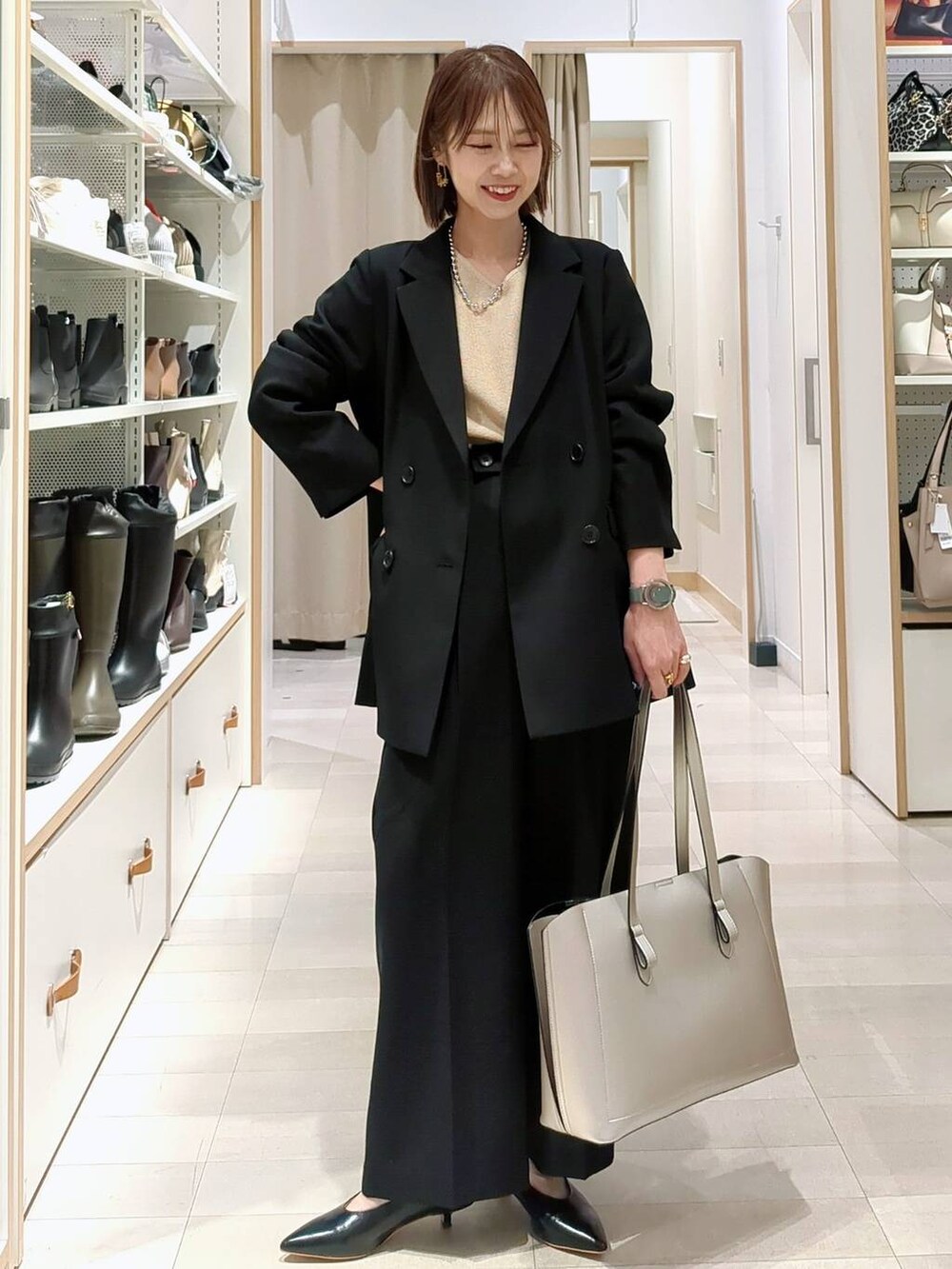 シルバー系のトートバッグ、ベージュ系のニット/セーター、ブラック系のその他パンツを着用したレディースの春コーディネートの2枚目の写真