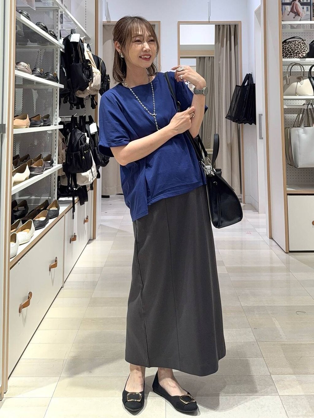 ブラック系のトートバッグ、ブラック系のパンプス、グレー系のその他パンツを着用したレディースの夏コーディネートの3枚目の写真