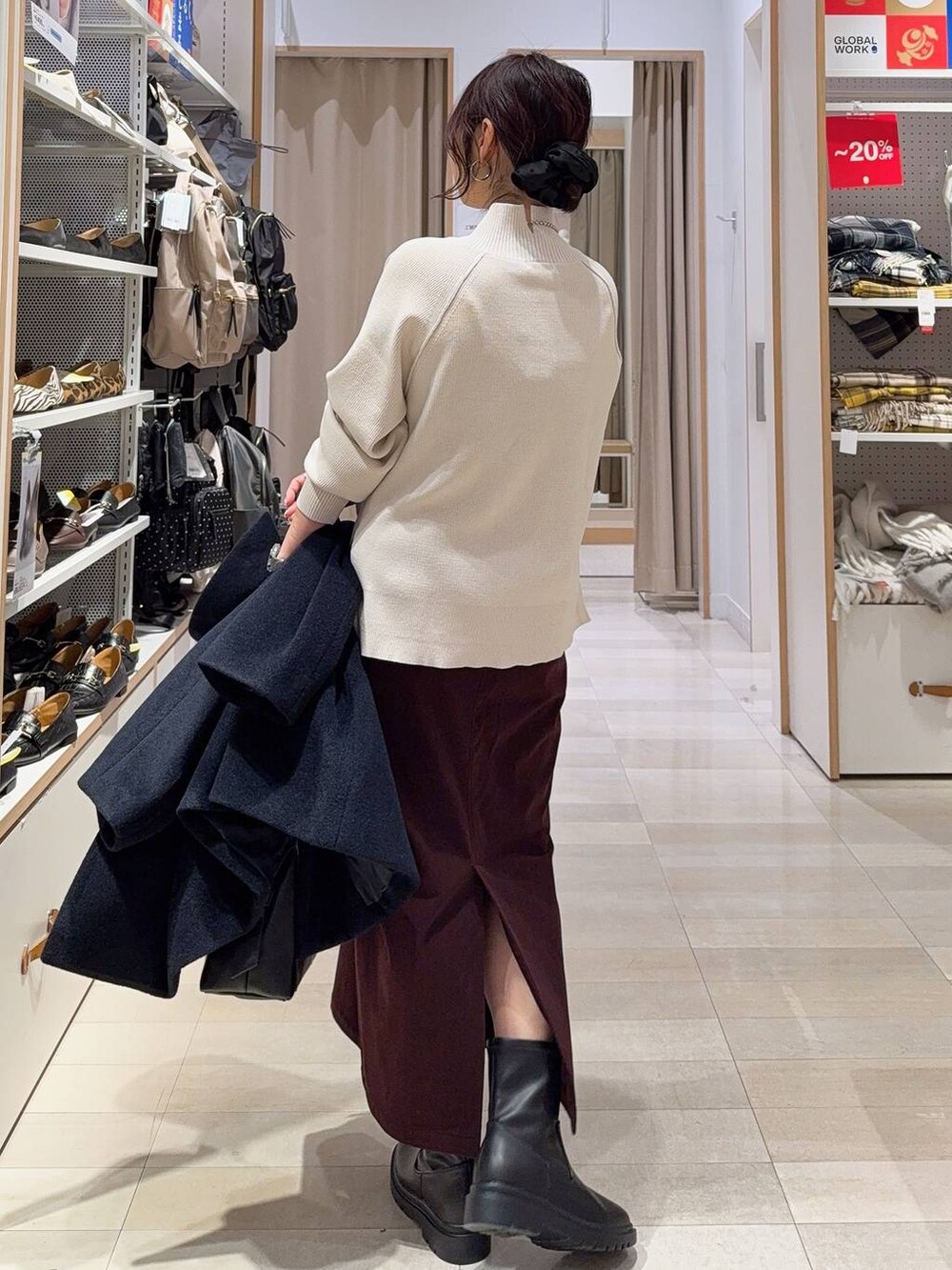 ブラック系のボストンバッグ、ブルー系のチェスターコート、レッド系のスカートを着用したレディースの冬コーディネートの7枚目の写真