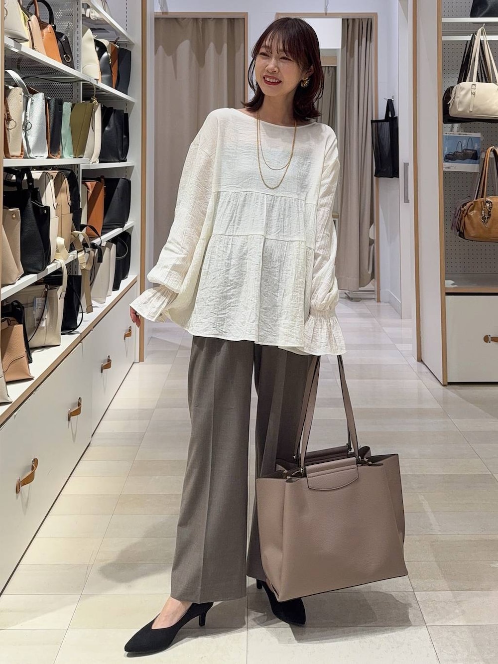 その他のパンプス、ブラウン系のスラックス、ブラック系のトートバッグを着用したレディースの春コーディネートの2枚目の写真