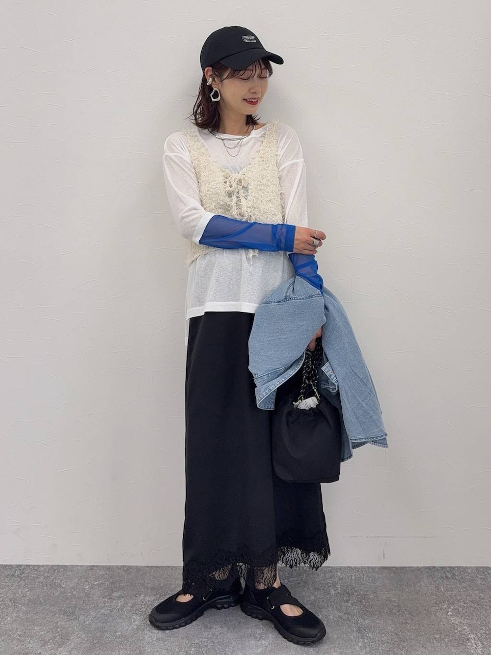 ブラック系のスニーカー、ホワイト系のベスト、シルバー系のネックレスを着用したレディースの春コーディネートの2枚目の写真