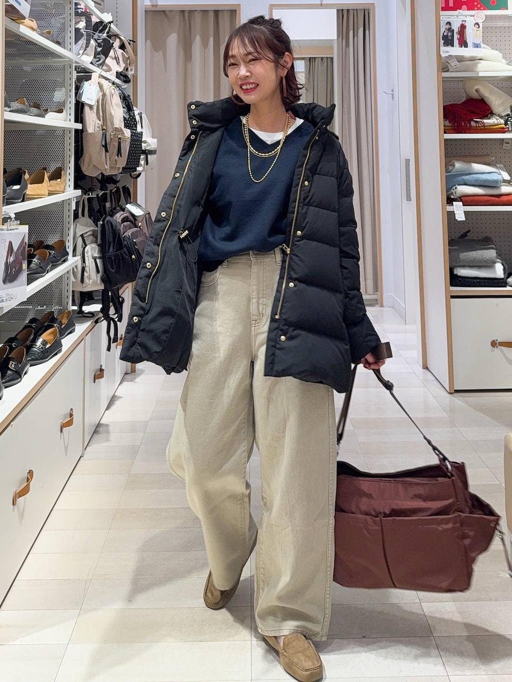 ブラック系のダウンジャケット/コート、ベージュ系のデニムパンツ、ホワイト系のTシャツ/カットソーを着用したレディースの冬コーディネートの2枚目の写真