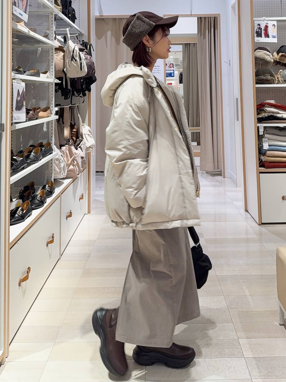 ブラック系のショルダーバッグ、ベージュ系のダウンジャケット/コート、ブラウン系のスカートを着用したレディースの秋コーディネートの3枚目の写真