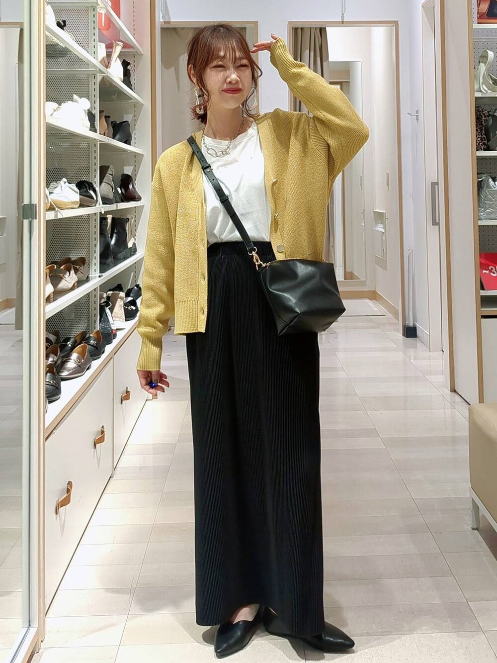 ベージュ系のデニムパンツ、ブラック系のショルダーバッグ、イエロー系のカーディガン/ボレロを着用したレディースの春コーディネートの3枚目の写真