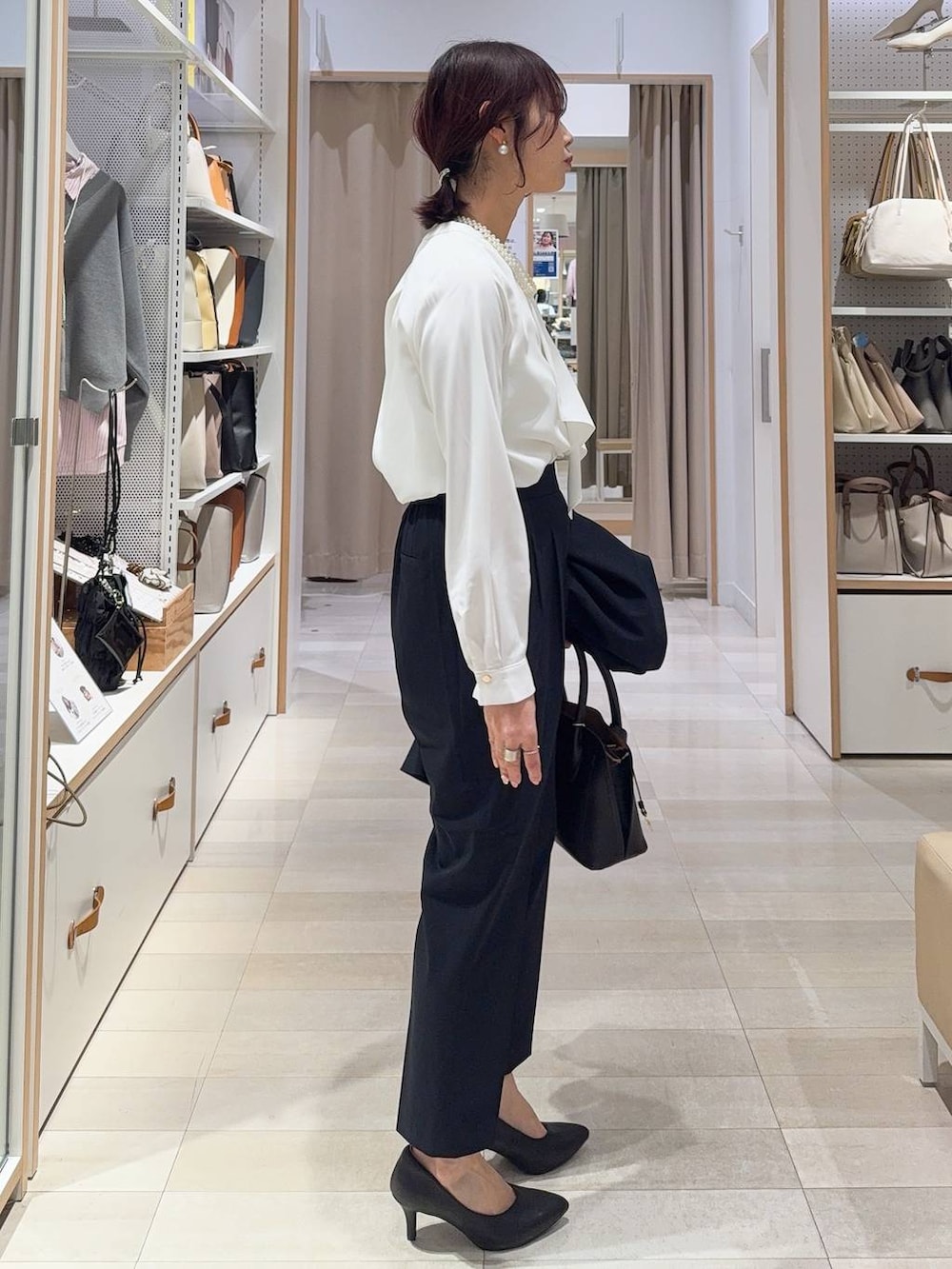 ブラック系のショルダーバッグ、ブルー系のスラックス、ホワイト系のシャツ/ブラウスを着用したレディースの冬コーディネートの6枚目の写真