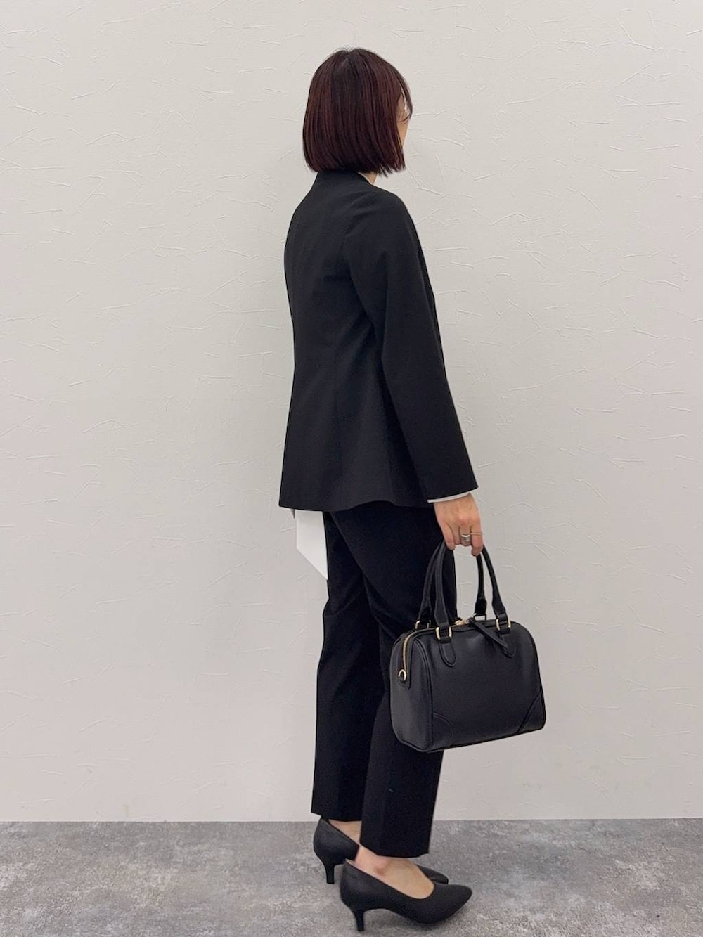 ブラック系のスラックス、ホワイト系のシャツ/ブラウス、ブラック系のボストンバッグを着用したレディースの秋コーディネートの2枚目の写真