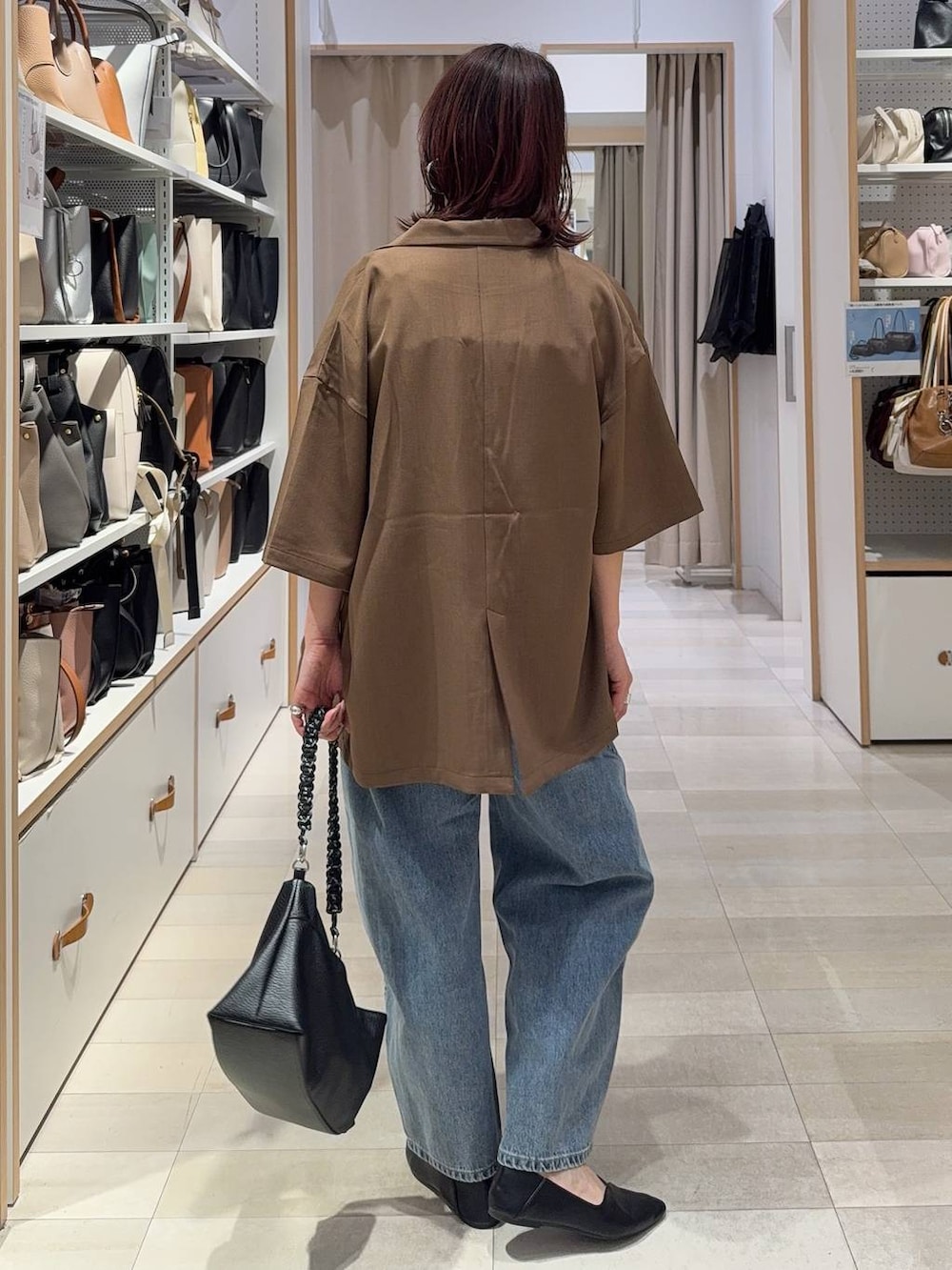 ブラック系のパンプス、ブルー系のデニムパンツ、シルバー系のネックレスを着用したレディースの春コーディネートの6枚目の写真