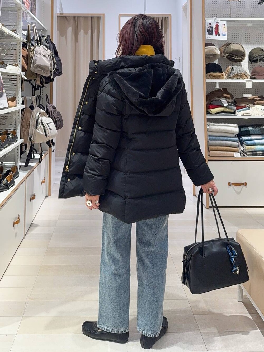 ブラック系のボストンバッグ、ブラック系のダウンジャケット/コート、ブルー系のデニムパンツを着用したレディースの秋コーディネートの6枚目の写真