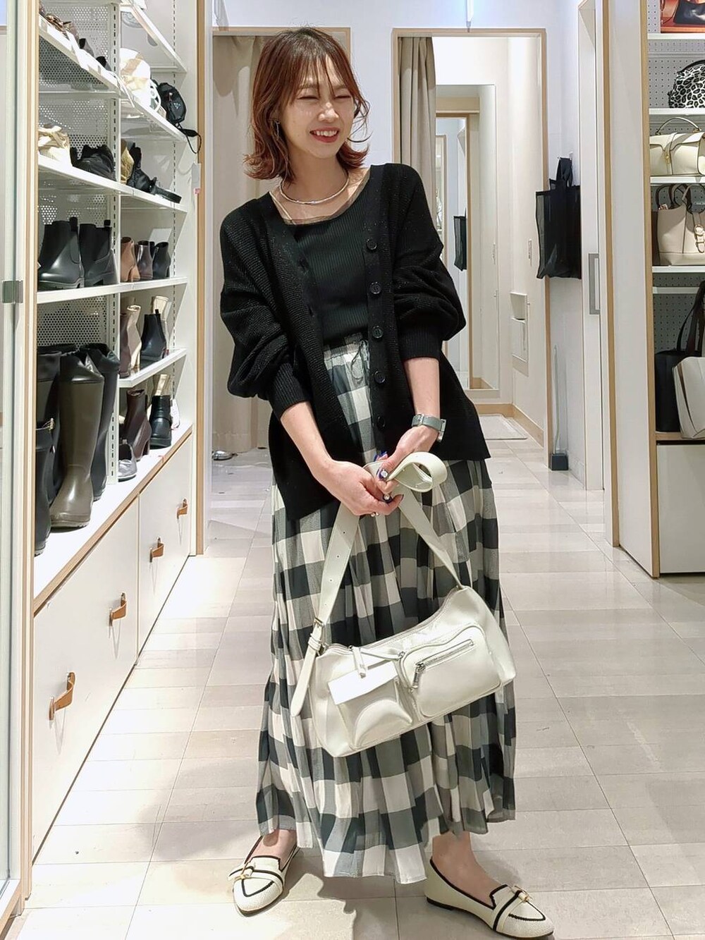 ホワイト系のスカート、ブラック系のスリッポン、オレンジ系のカーディガン/ボレロを着用したレディースの春コーディネートの3枚目の写真