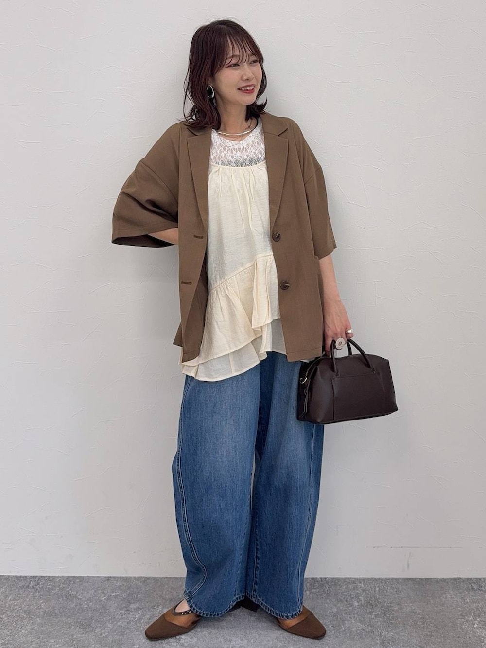 ブルー系のデニムパンツ、ブラウン系のキャミソール、ブラウン系のボストンバッグを着用したレディースの春コーディネートの2枚目の写真