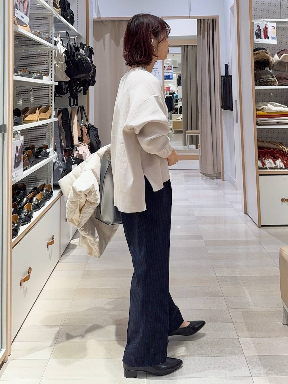 シルバー系のトートバッグ、ベージュ系のダウンジャケット/コート、ホワイト系のニット/セーターを着用したレディースの冬コーディネートの6枚目の写真