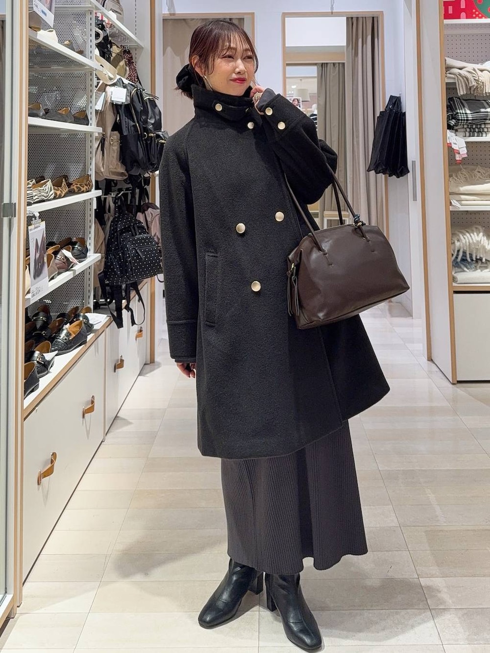 ブラウン系のボストンバッグ、ブラック系のチェスターコート、ホワイト系のTシャツ/カットソーを着用したレディースの冬コーディネートの3枚目の写真