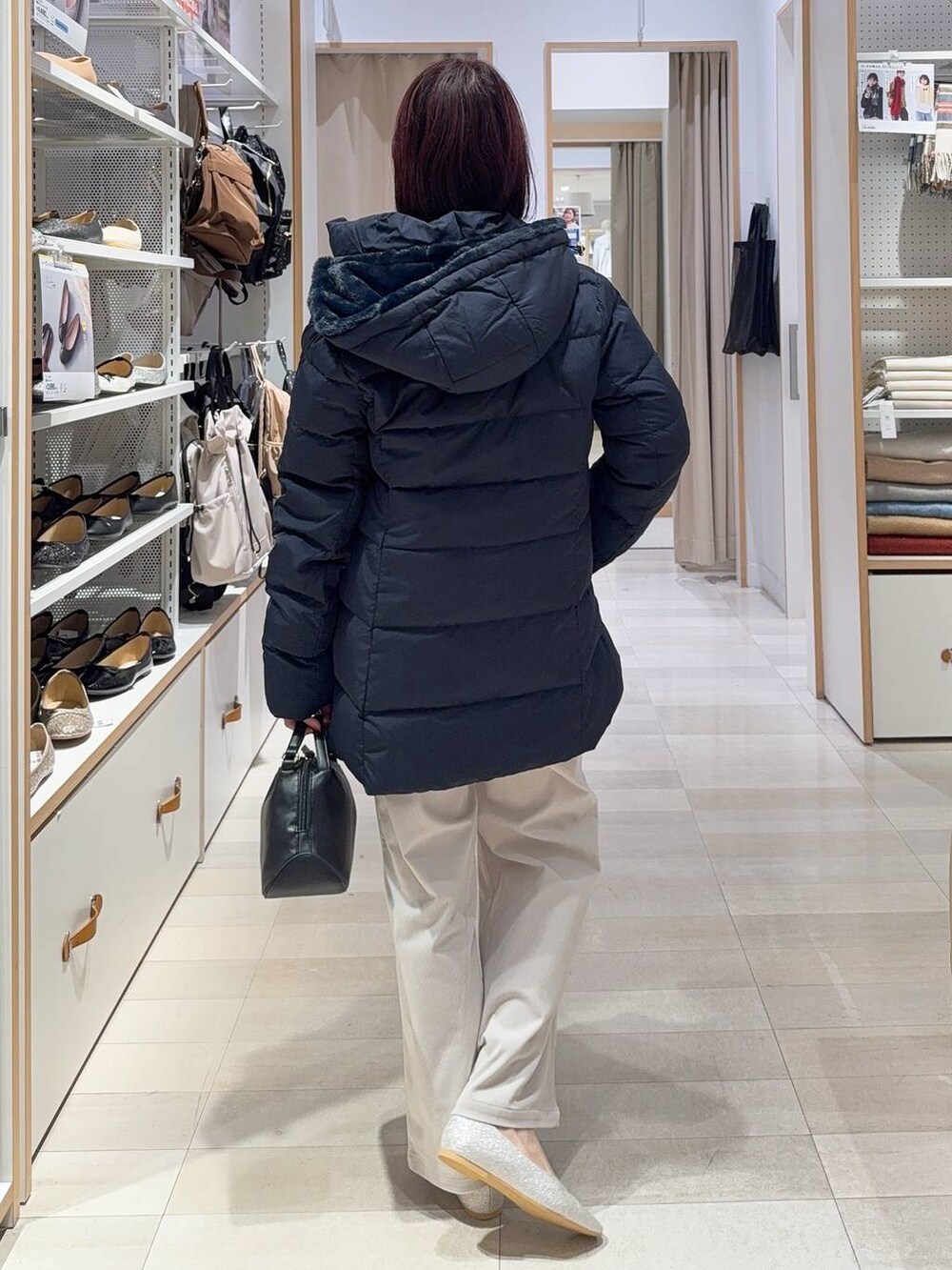 ブラック系のショルダーバッグ、シルバー系のパンプス、ブルー系のダウンジャケット/コートを着用したレディースの秋コーディネートの5枚目の写真