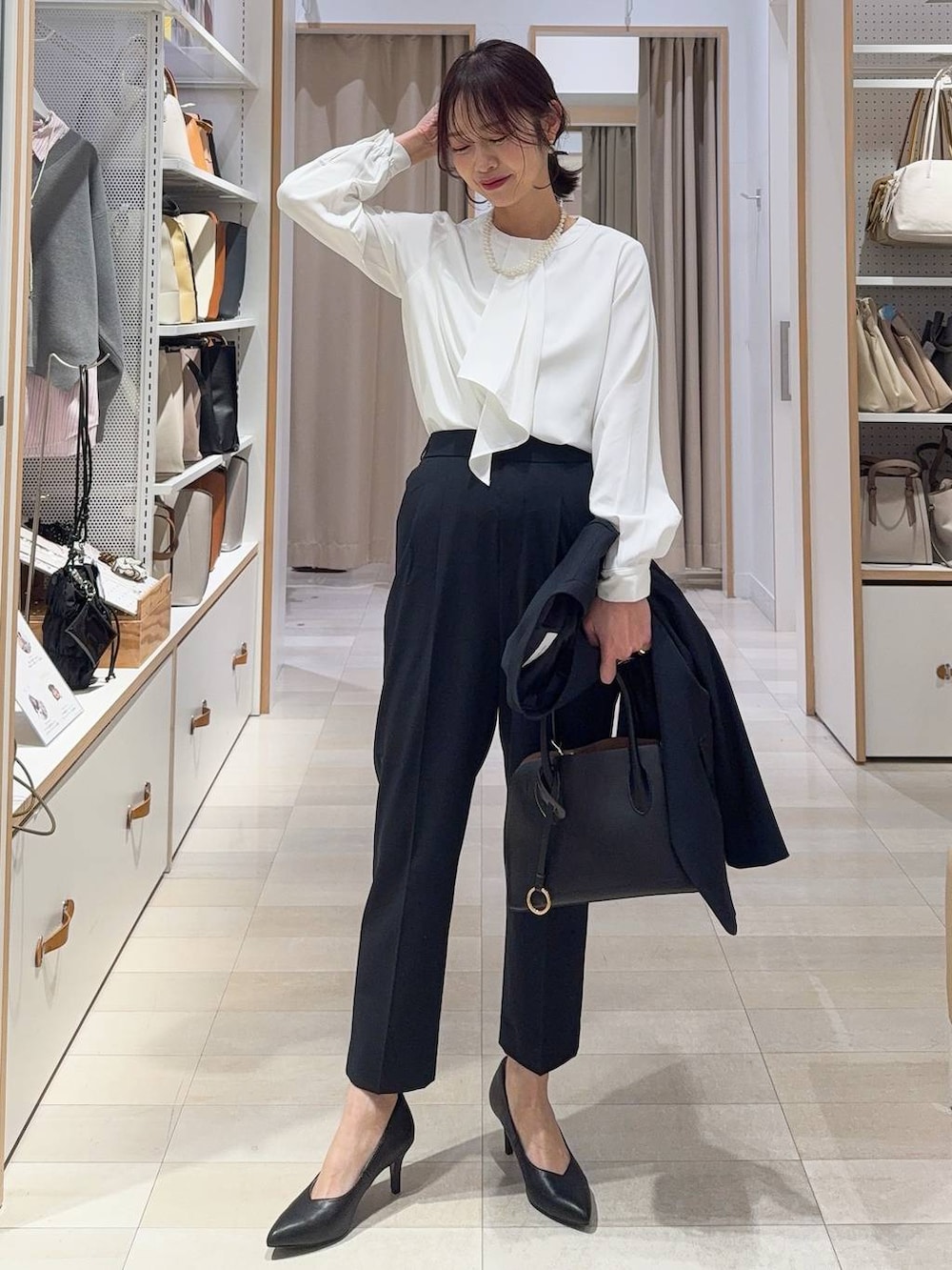 ブラック系のショルダーバッグ、ブルー系のスラックス、ホワイト系のシャツ/ブラウスを着用したレディースの冬コーディネートの2枚目の写真