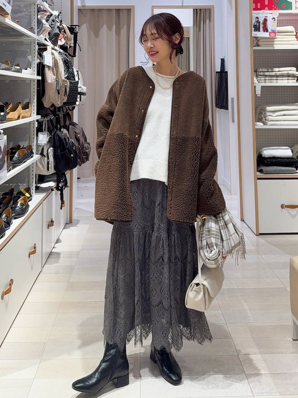 ベージュ系のショルダーバッグ、ブラック系のブーツ、ブラウン系のテーラードジャケットを着用したレディースの冬コーディネートの2枚目の写真