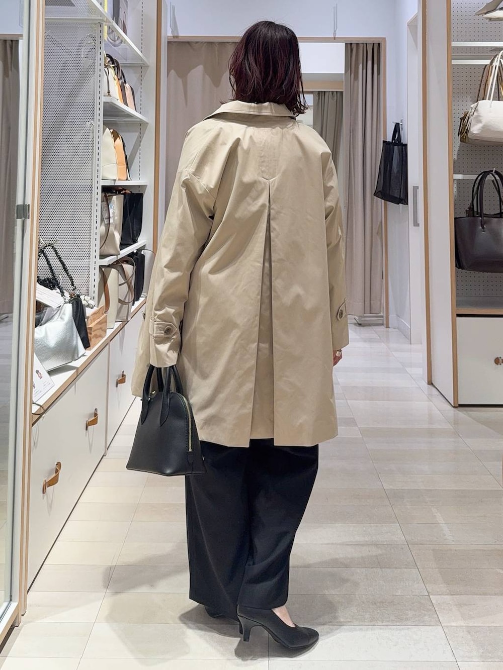 ブラック系のショルダーバッグ、ブラック系のパンプス、ベージュ系のステンカラーコートを着用したレディースの冬コーディネートの4枚目の写真