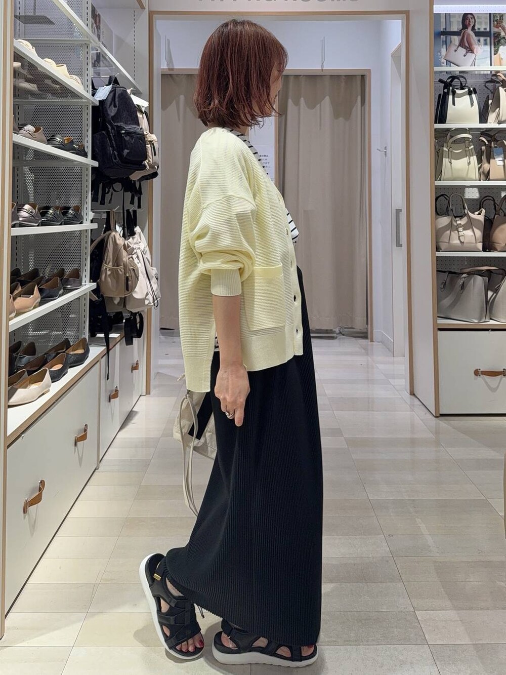 ブラック系のスカート、イエロー系のカーディガン/ボレロ、ホワイト系のトートバッグを着用したレディースの夏コーディネートの6枚目の写真