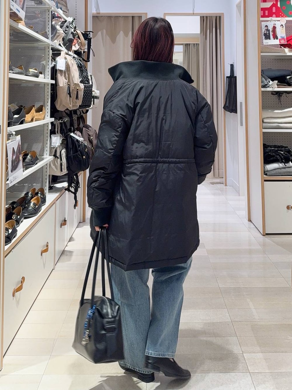 ブラック系のダウンジャケット/コート、ブラック系のボストンバッグ、ブルー系のデニムパンツを着用したレディースの冬コーディネートの6枚目の写真