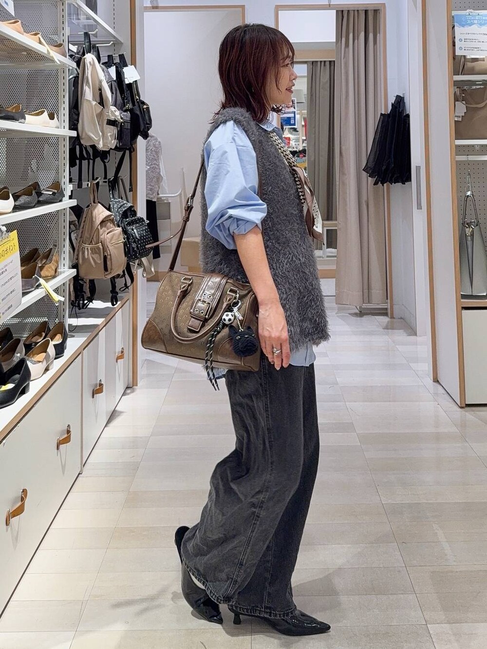 グリーン系のボストンバッグ、ブルー系のシャツ/ブラウス、グレー系のベストを着用したレディースの秋コーディネートの6枚目の写真