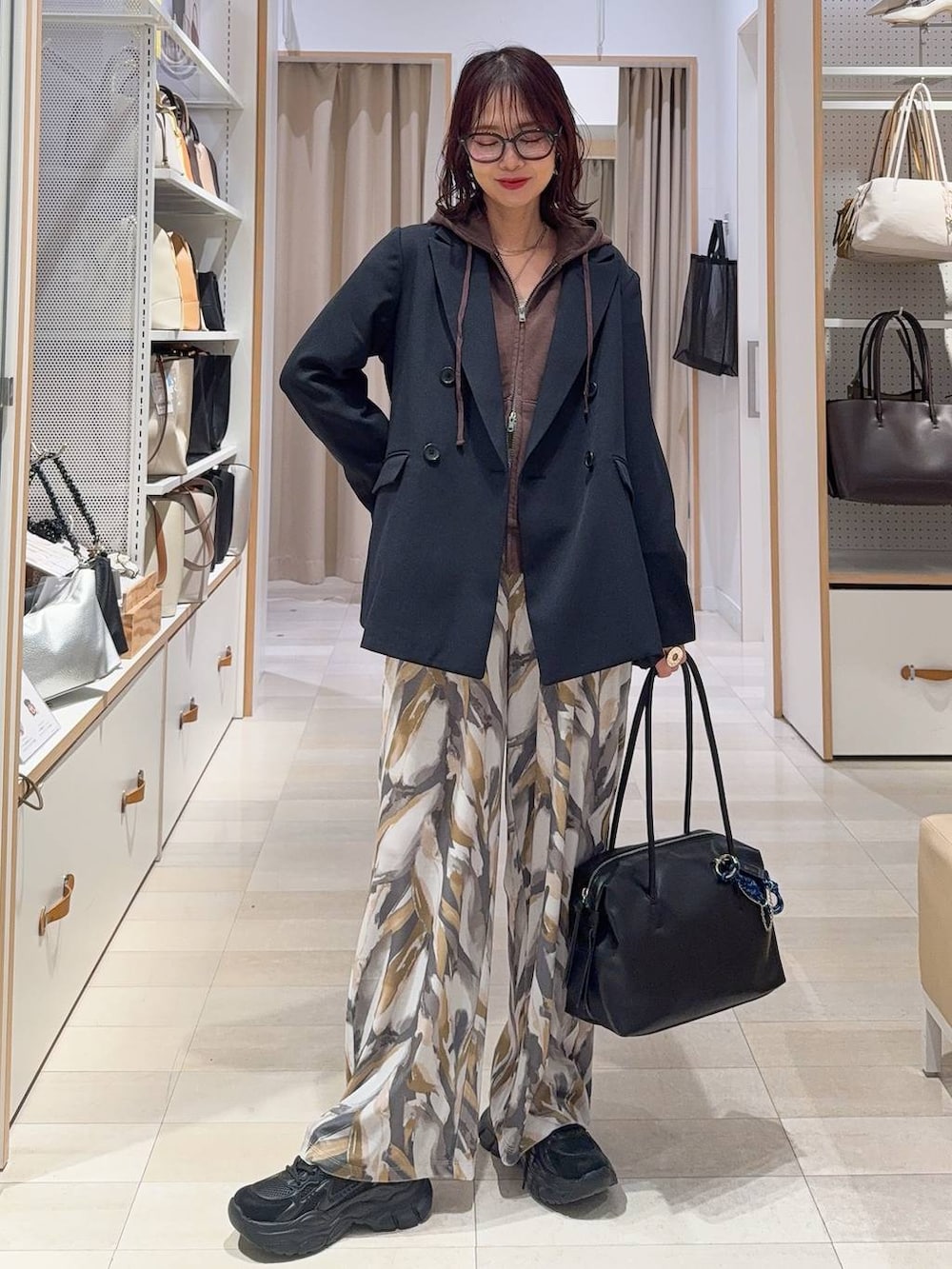 ブラック系のボストンバッグ、ブラック系のスニーカー、ブルー系のテーラードジャケットを着用したレディースの冬コーディネートの2枚目の写真