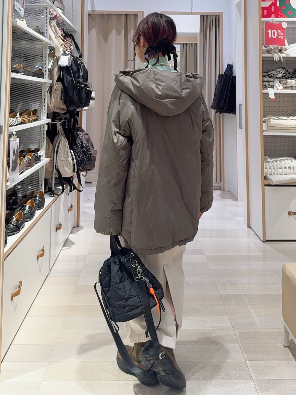 ブラウン系のダウンジャケット/コート、グレー系のスカート、ブラック系のハンドバッグを着用したレディースの冬コーディネートの7枚目の写真