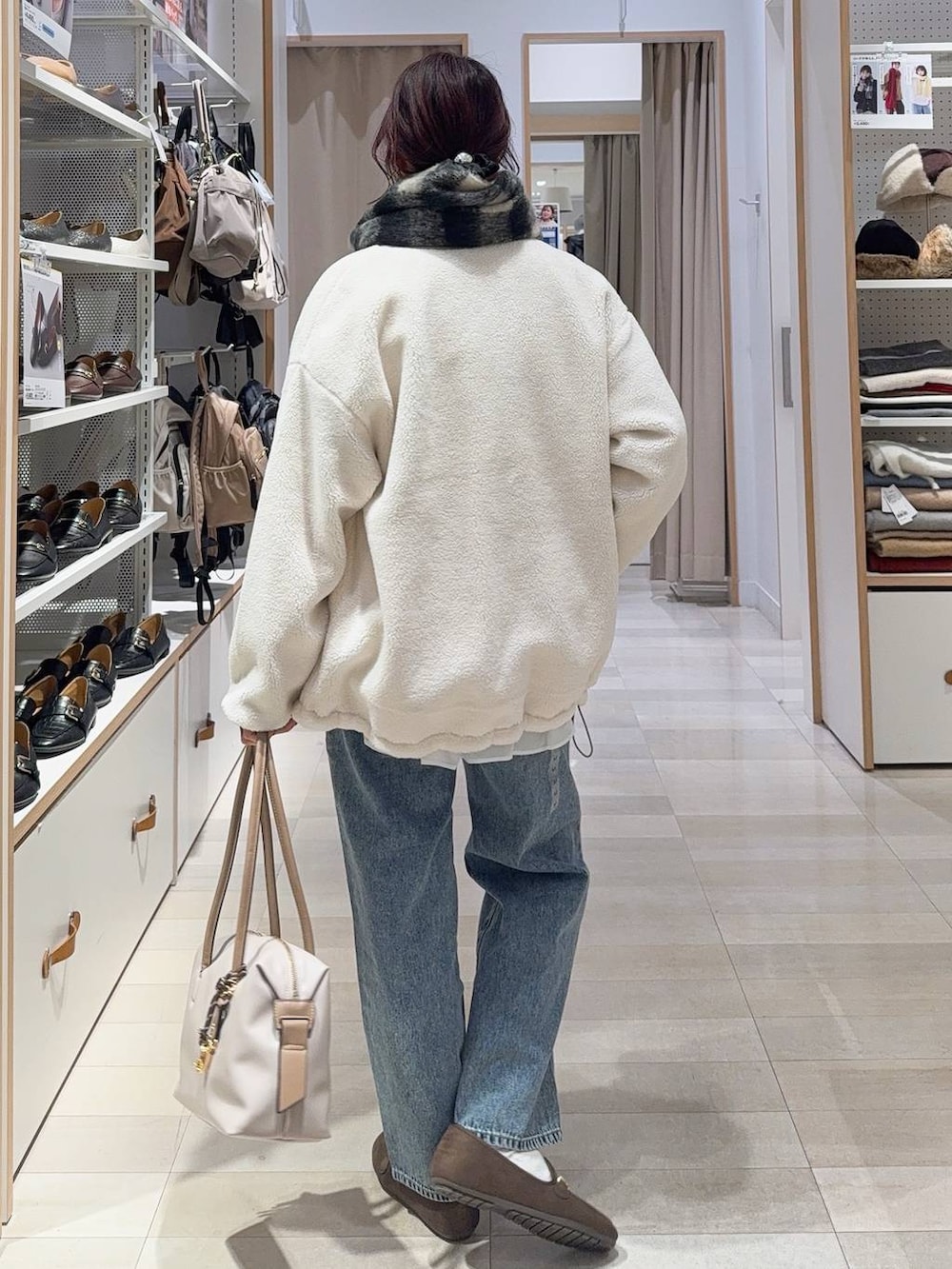 ホワイト系のボストンバッグ、ホワイト系のブルゾン、ブルー系のデニムパンツを着用したレディースの秋コーディネートの7枚目の写真