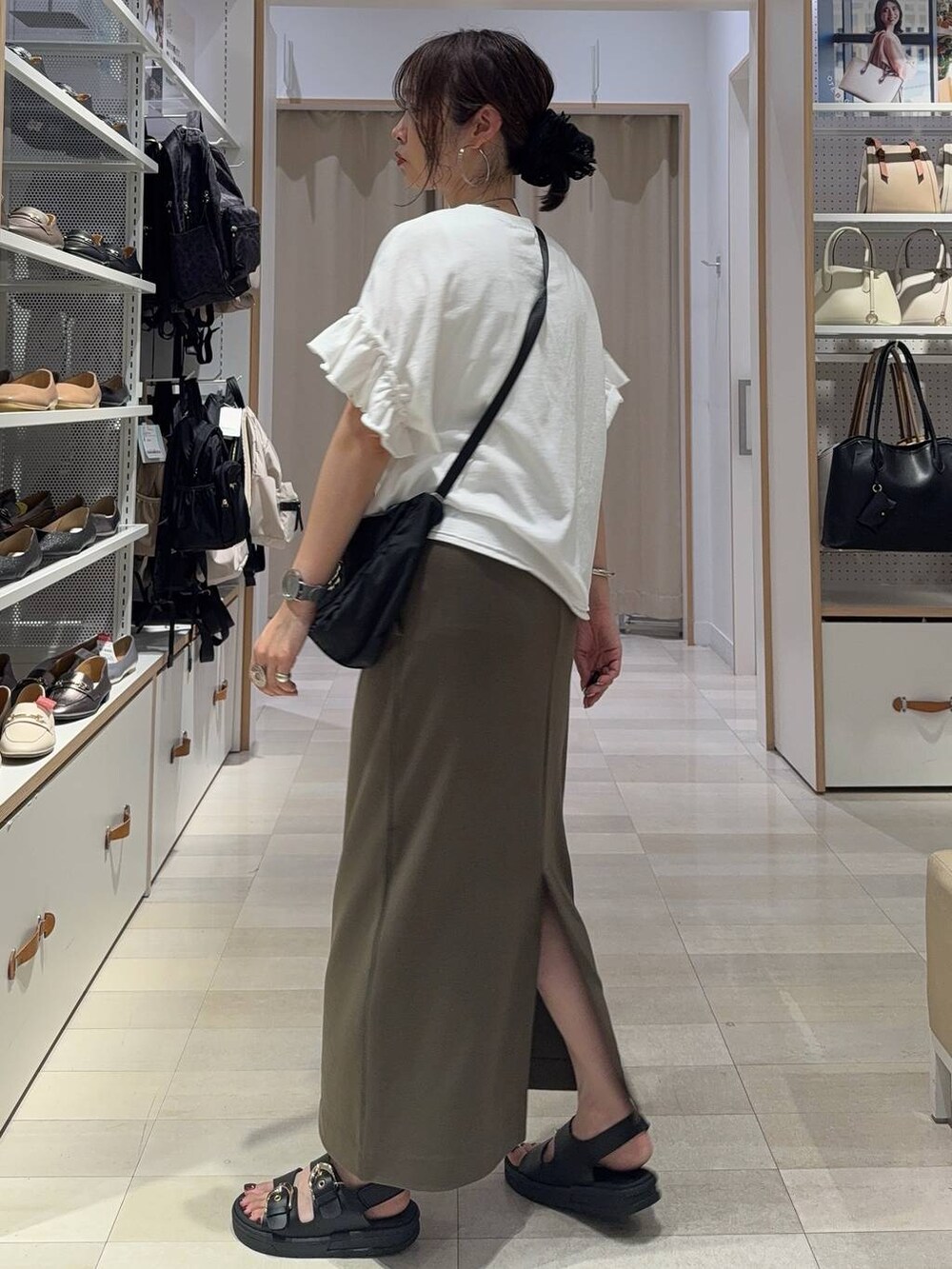 ブラック系のショルダーバッグ、ホワイト系のTシャツ/カットソー、グリーン系のスカートを着用したレディースの夏コーディネートの5枚目の写真