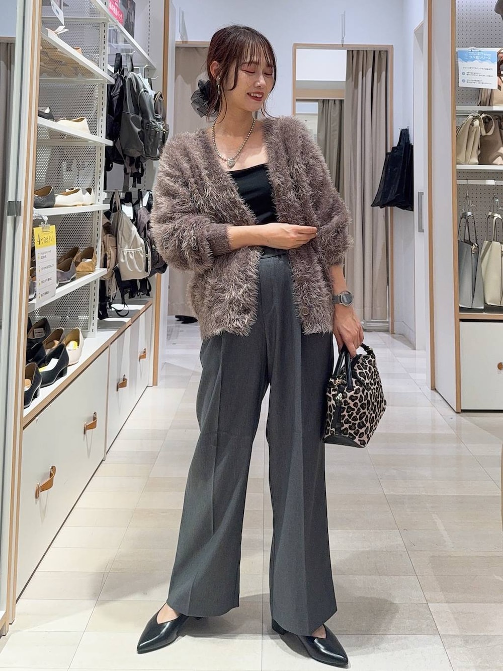 ブラック系のパンプス、ブラック系のボストンバッグ、ブルー系のデニムパンツを着用したレディースの秋コーディネートの3枚目の写真